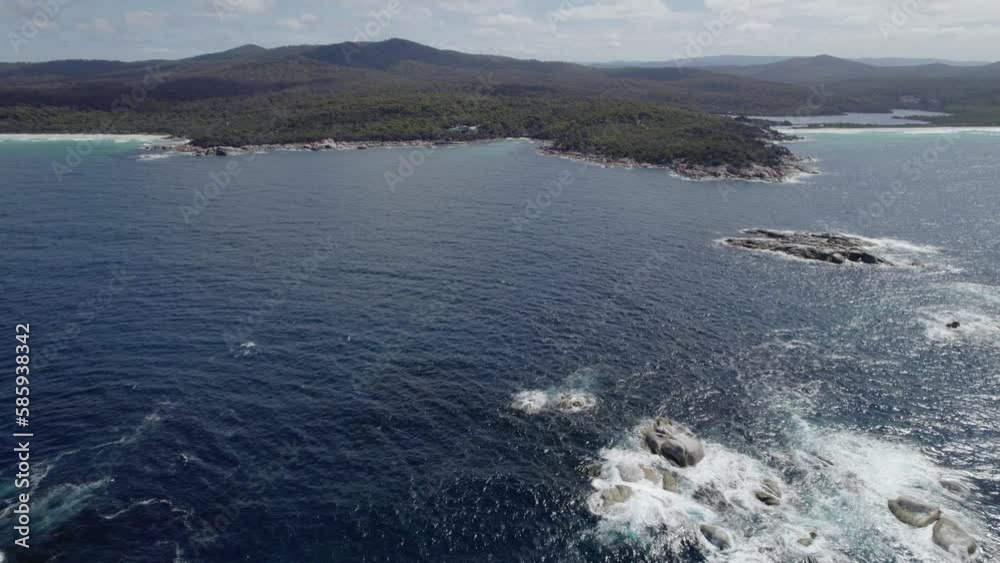 Rocky Outcrops And Foamy Waves In The Tasman Sea In Binalong Bay, Tasmania, Sloop Rock Lookout In Background. wide aerial Rocky Outcrops And Foamy Waves In The Tasman Sea In Binalong Bay, Tasmania, Sloop Rock Lookout In Background. wide aerial
