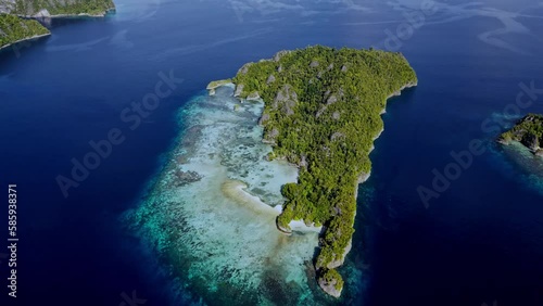 Aerial Footage. Small tropical island surrounded by shallow reefs in crystal clear water photo