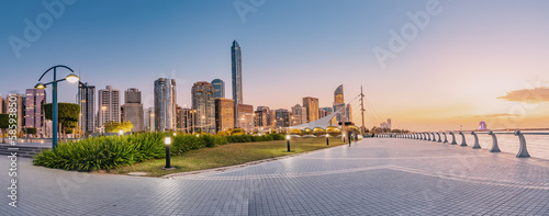 breathtaking view of Abu Dhabi s embankment skyline as the sun sets in the horizon  casting a warm orange glow on the towering skyscrapers