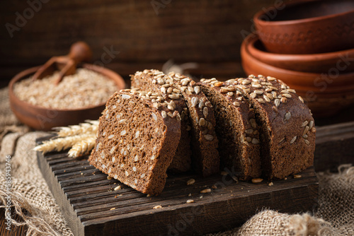 Sliced dark rye bread with sunflower seeds on a wooden board, rustic style. Healthy rye bread