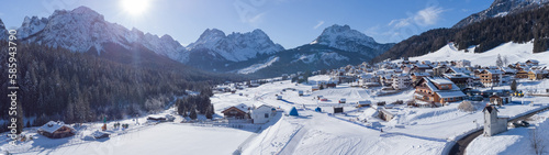 Aerial drone panorama of village of Sappada in italian Dolomites on a sunny winter day packed with snow. Beautiful alpine village in Dolomites.