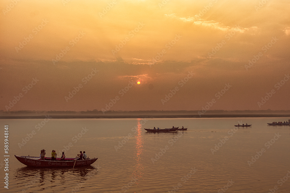 Peaceful sunrise, sunset warm landscape of river with people on the boats. Ganga river bank. Varanasi, India.