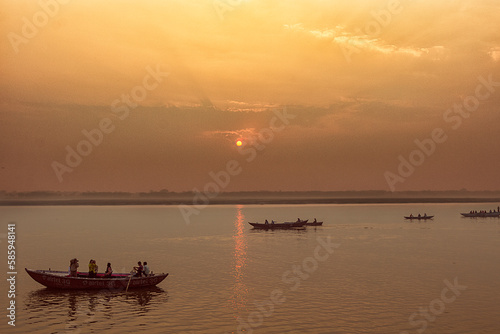 Peaceful sunrise, sunset warm landscape of river with people on the boats. Ganga river bank. Varanasi, India.
