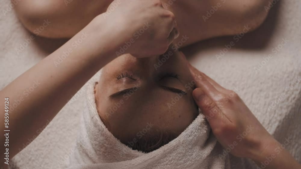 Beautiful woman with closed eyes relaxing in spa salon getting face massage in beauty spa. Serene woman relaxing in a beauty center. Professional beauty salon.