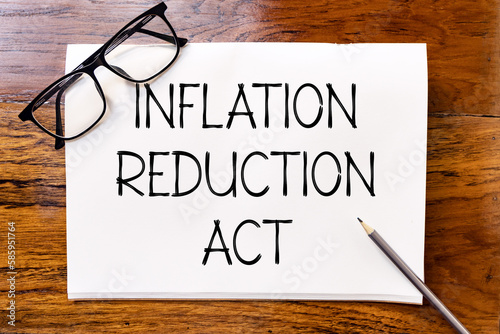 Inflation reduction act text on blank notebook paper on wooden table with pencil and glasses aside. Business concept and legal concept about inflation reduction act. photo