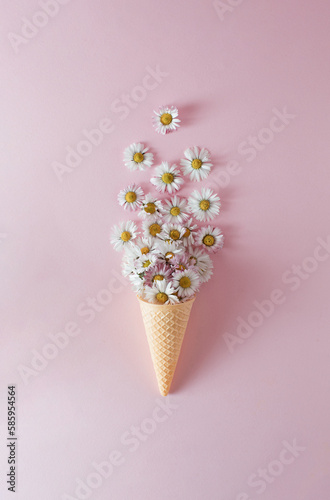 Ice cream cone with daisy flower and leaves on pink background. Flat lay. Minimal summer concept.