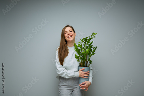 Happy woman holding home plant in pot.