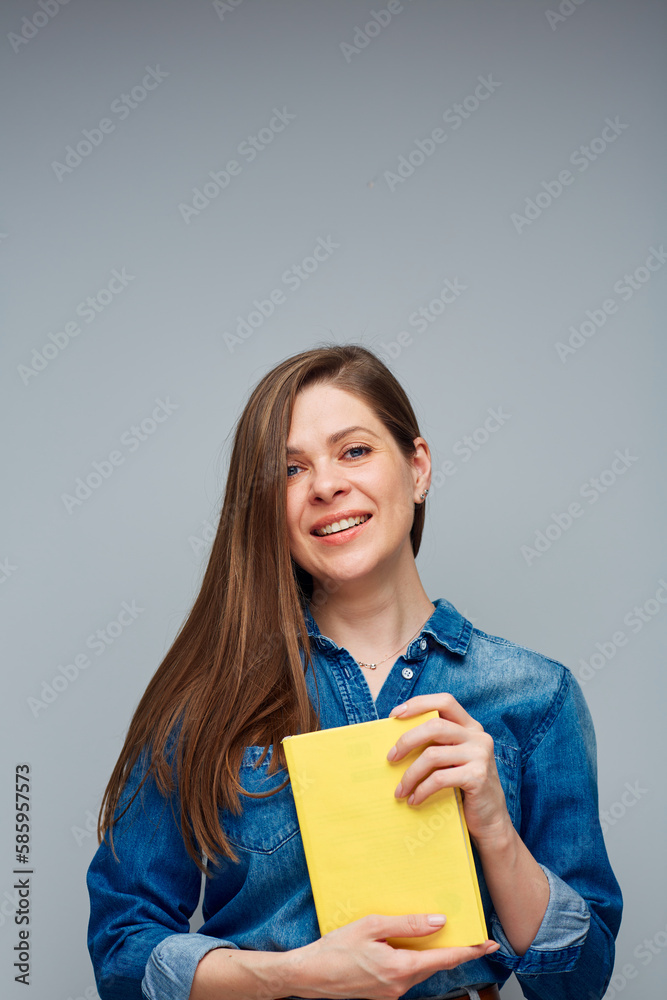 Fototapeta premium Smiling woman student in blue shirt holding yellow book.