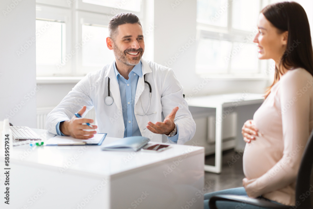 Pregnant woman visiting doctor man at clinic, therapist giving recommendations to happy expecting lady Pregnant woman visiting doctor man at clinic, therapist giving recommendations to happy expecting lady
