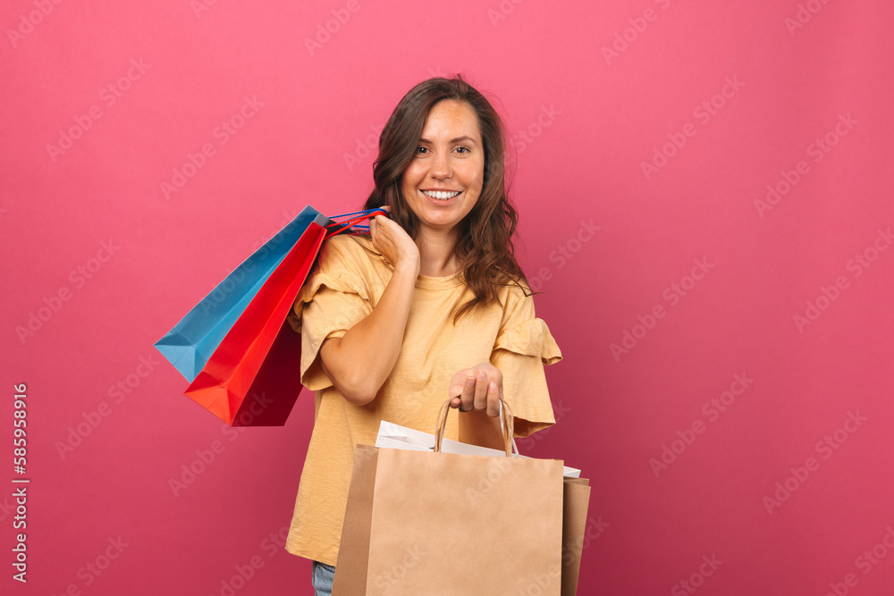 Cheerful young woman is holding some shopping bags over pink background. Cheerful young woman is holding some shopping bags over pink background.