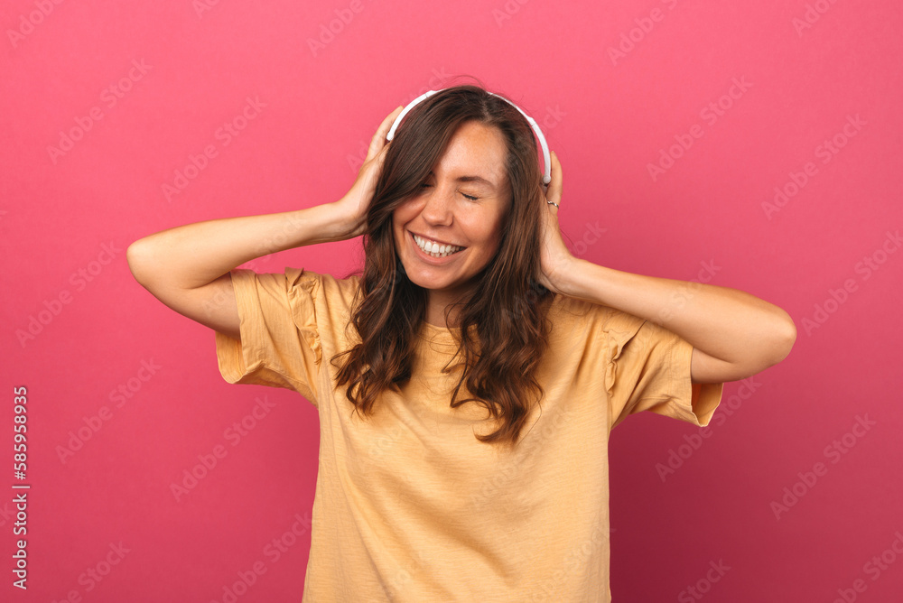 Young smiling woman is wearing headphones and having fun with eyes closed.