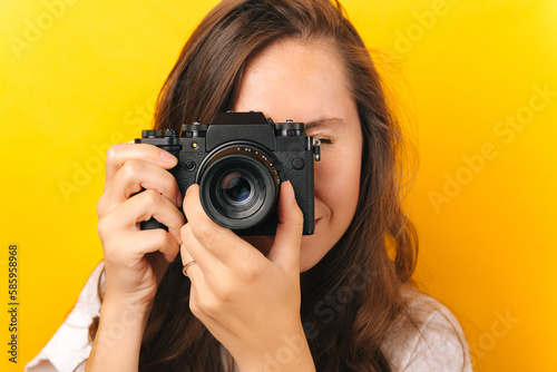 Close up crop studio shot of a young woman taking a picture with a pro camera. © Vulp