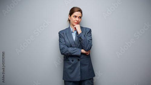 Portrait of thinking serious business woman on gray background.