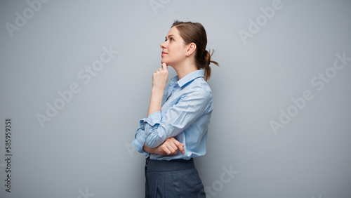 Portrait of serious thinking business woman on gray background looking away.