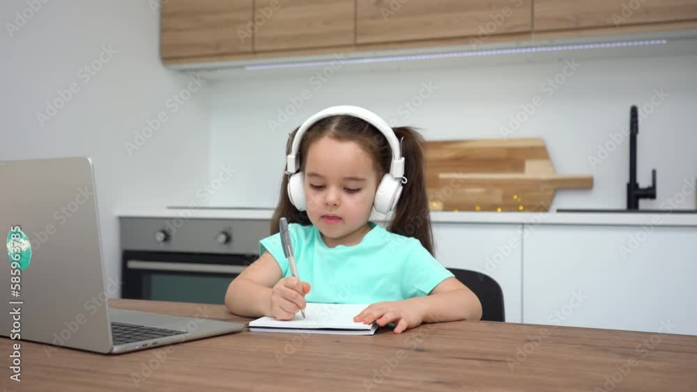 Cute little girl drawing in a notebook during a preschool online lesson at home. Cute little girl drawing in a notebook during a preschool online lesson at home.