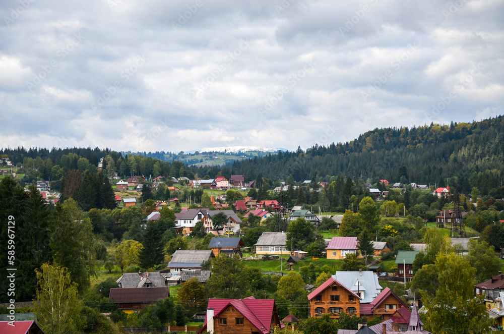 Fototapeta premium Panorama of the green hilly valley with houses and a mountainous backdrop at the Vorokhta village, Carpathian Mountains, Ukraine