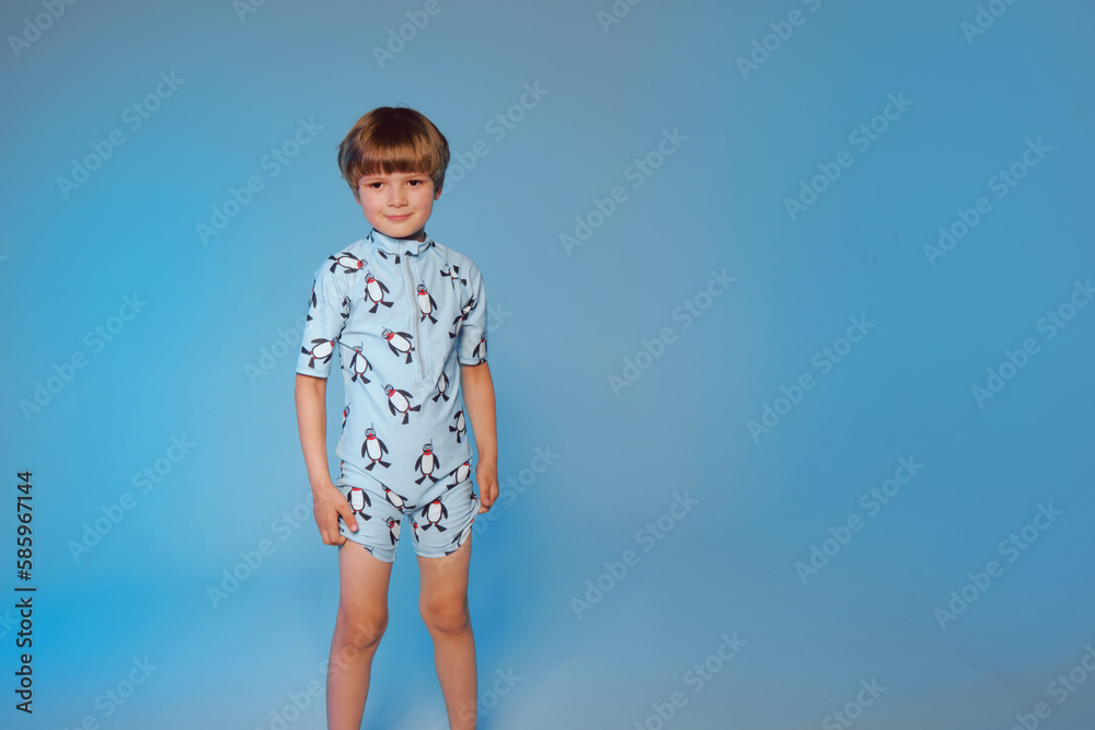 Happy cute boy 6 years old wearing a swimsuit at the blue background Happy cute boy 6 years old wearing a swimsuit at the blue background