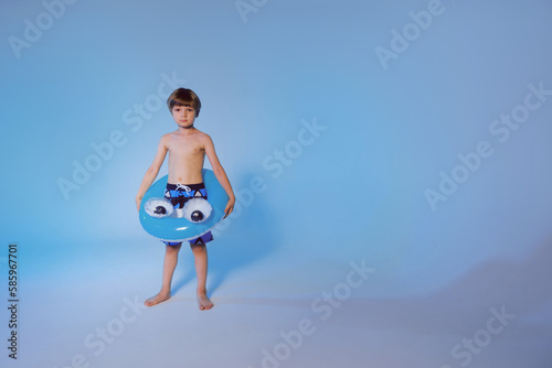 Happy cute boy 6 years old with a life buoy at the blue background