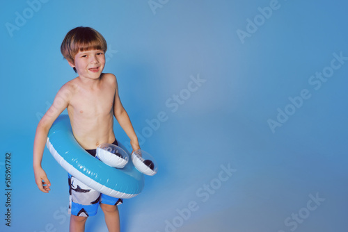 Happy cute boy 6 years old with a life buoy at the blue background