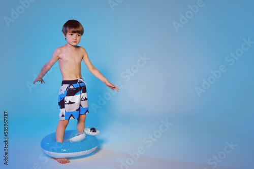 Happy cute boy 6 years old with a life buoy at the blue background