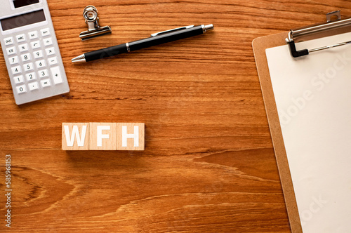 There is wood cube with the word WFH.It is an abbreviation for Work From Home as eye-catching image.
