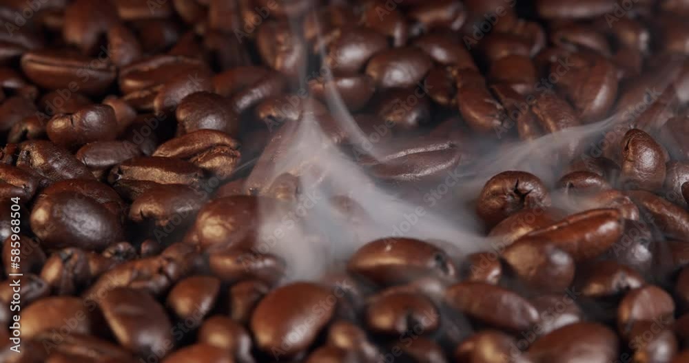 Freshly roasted coffee beans with a slow swirl of smoke. Close-up view of coffee roasting, the smoke of roasting coffee beans slowly drifts past. Freshly roasted coffee beans with a slow swirl of smoke. Close-up view of coffee roasting, the smoke of roasting coffee beans slowly drifts past.