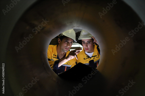 two engineers seen through a large pipeline shaft, metal industry