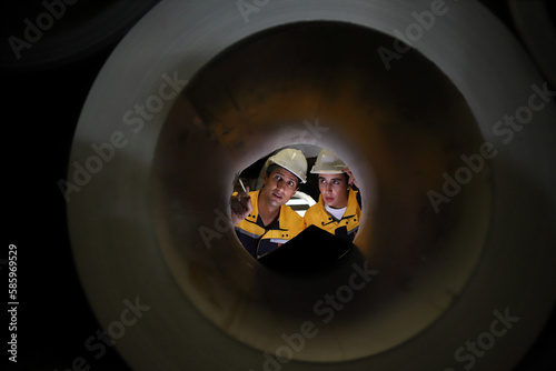two engineers seen through a large pipeline shaft, metal industry