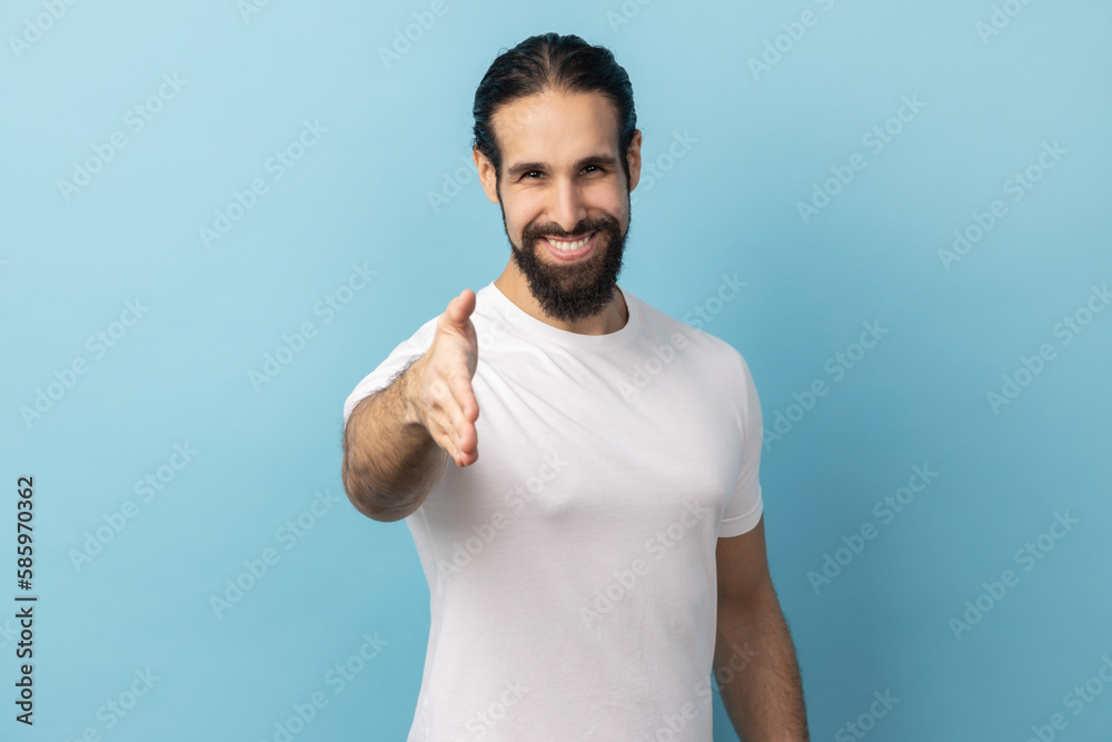 Man standing and looking at camera with toothy smile and giving hand to greeting or handshake.