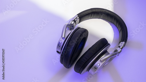 Silver headphones on neon background. Bass headphones