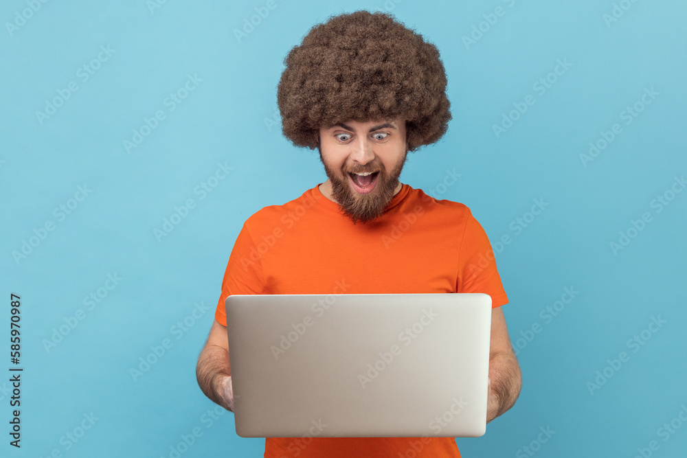 Man holding notebook and looking at display with excitement, playing computer games. Man holding notebook and looking at display with excitement, playing computer games.