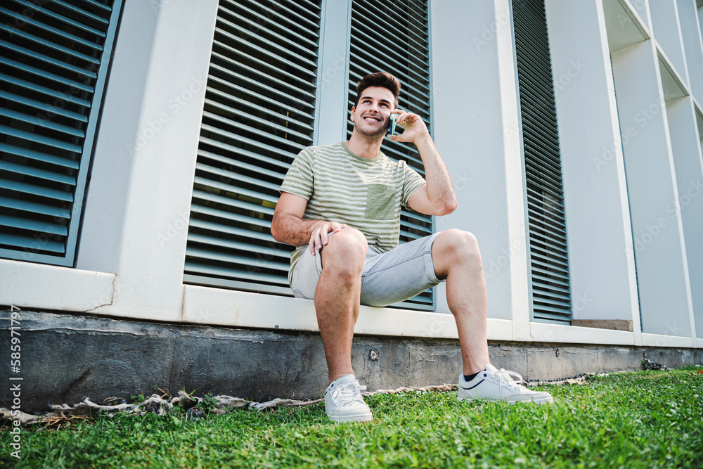 One isolated handsome man having a cell phone call with a friend. Happy male teenager talking using a smartphone. Young guy smiling and speaking by mobile. Communication concept. High quality photo One isolated handsome man having a cell phone call with a friend. Happy male teenager talking using a smartphone. Young guy smiling and speaking by mobile. Communication concept. High quality photo