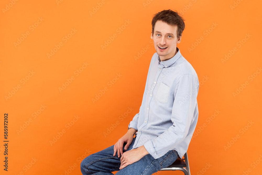 Handsome attractive man sitting and looking at camera with positive expression. Handsome attractive man sitting and looking at camera with positive expression.