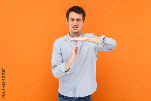 Serious self confident man making timeout gesture, demonstrating limit, asking to stop.
