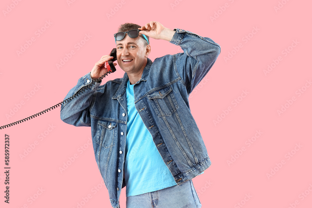 Mature man talking by telephone on pink background Mature man talking by telephone on pink background