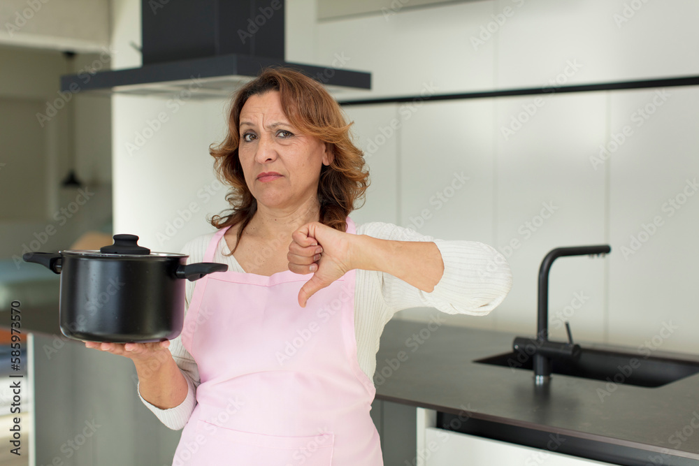middle age pretty woman feeling cross,showing thumbs down. cooking at home concept middle age pretty woman feeling cross,showing thumbs down. cooking at home concept