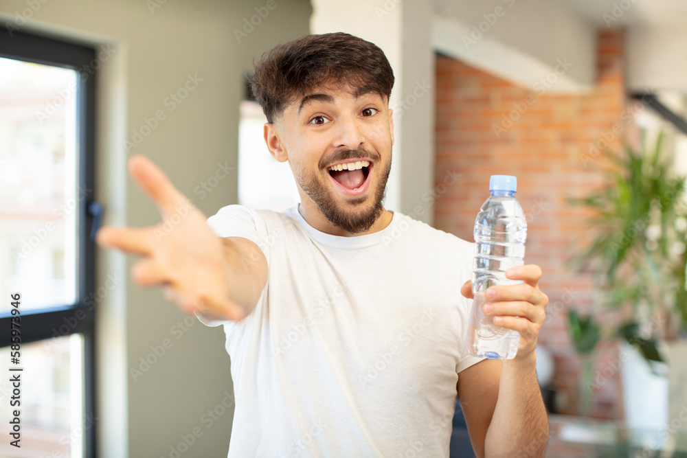 young handsome man smiling happily and offering or showing a concept. water bottle concept young handsome man smiling happily and offering or showing a concept. water bottle concept