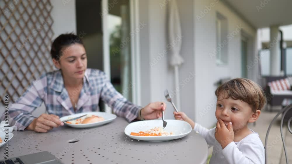 Mother feeding little boy lunch at home backyard. Little boy eating meal. 2 year old kid. Portrait face closeup child Mother feeding little boy lunch at home backyard. Little boy eating meal. 2 year old kid. Portrait face closeup child