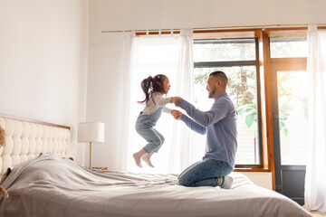 little asian girl jumping on bed at home with dad, korean man playing with daughter, happy family, dad love concept