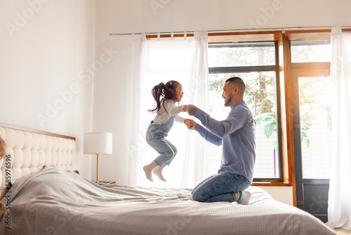little asian girl jumping on bed at home with dad, korean man playing with daughter, happy family, dad love concept