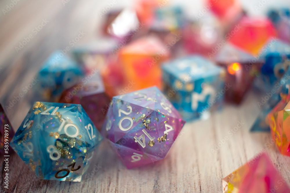 Resin dice on a wooden table, a blue die and purple die sit in the foreground