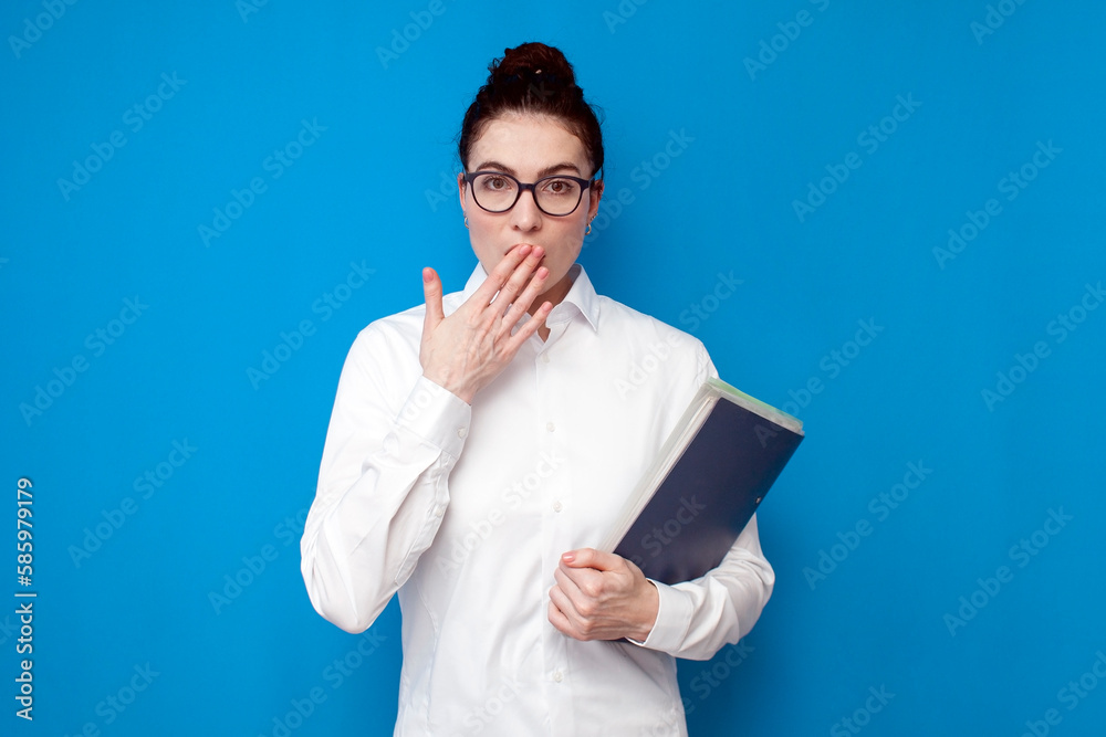 shocked woman office worker in white shirt and glasses holds folder with documents, girl financier