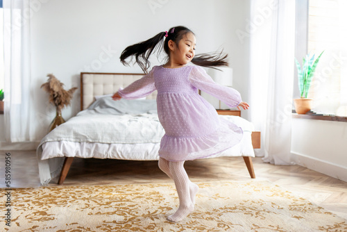 Tablou pe pânză little Asian girl in dress dances and spins at home, Korean child in festive out