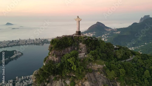 Rio de Janeiro, Brazil - March 21, 2023: Christ the Redeemer statue on top of the Corcovado Mountain with the Sugarloaf Mountain in the  horizon on sunrise.