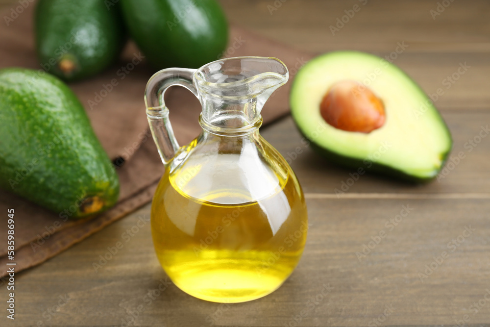 Jug with oil and ripe fresh avocados on wooden table, closeup Jug with oil and ripe fresh avocados on wooden table, closeup