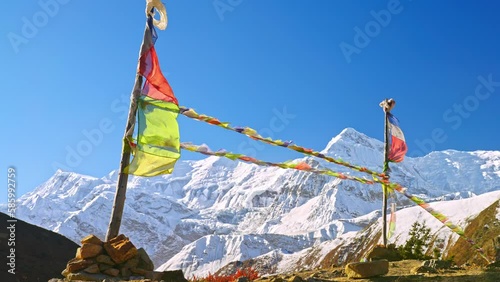 Slow motion of prayer flags blowing in the wind with majestic views of a snowy Annapurna Himalayan mountain, Nepal