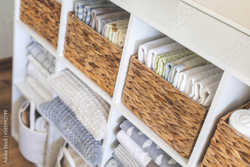 Neatly folded linen cupboard shelves storage at eco friendly straw basket placed closet organizer