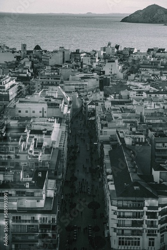 Vertical grayscale shot of a cityscape by the sea