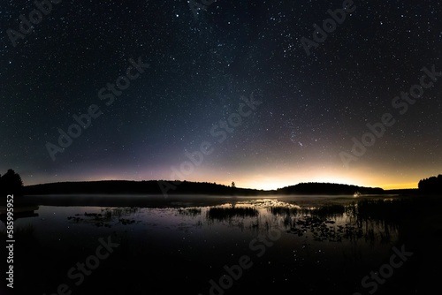 a large body of water under a clear sky with a star filled sky © Joseph Lipski/Wirestock Creators