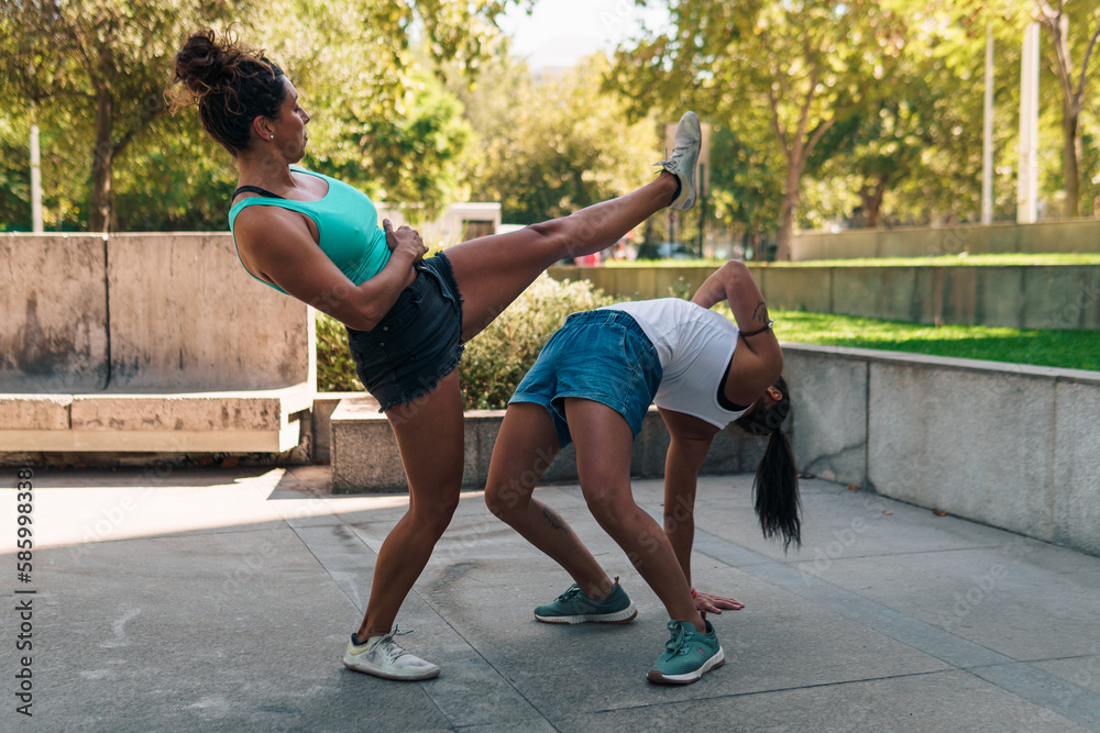 Fototapeta premium bellas mujeres deportistas practicando patadas de capoeira en la ciudad en un día soleado.